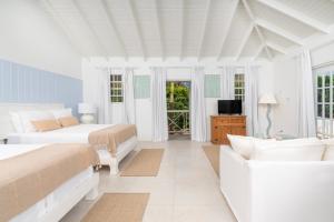 a white bedroom with two beds and a couch at Gibbs Cottages in Saint Peter