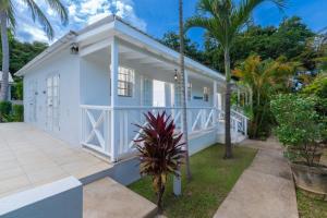 a white house with a porch and palm trees at Gibbs Cottages in Saint Peter