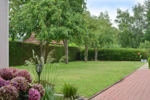 a garden with flowers and trees and a sidewalk at Ferienwohnung Sonnenberg, 25502 in Weener +8 photos