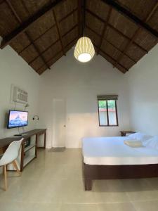 a bedroom with a bed and a desk and a television at Villa Peray Siargao in General Luna