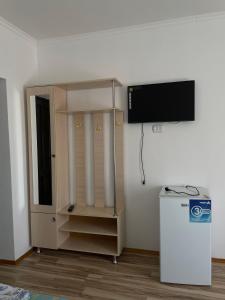 a room with a tv on a wall with a cabinet at Guest House Arbat in Cholpon-Ata +24 photos