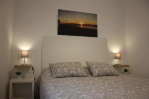 a bedroom with a bed with two lamps and a painting on the wall at TangoSierraResidences in Alcochete