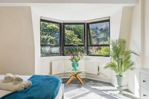 a bedroom with a bed and a table and windows at Windsor Castle Views - Spacious Flat - By Tempstay in Windsor