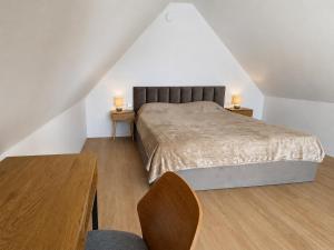 a bedroom with a large bed and two tables at Pirtelių resort - Pilkasis namelis in Kiauleikiai