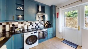 a kitchen with blue cabinets and a washer and dryer at Buckland Mews in Abingdon