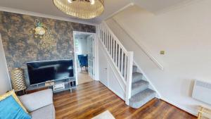 a living room with a staircase and a flat screen tv at Buckland Mews in Abingdon
