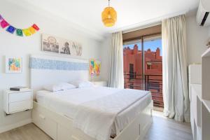 a white bedroom with a bed and a balcony at Veras Home in La Tejita