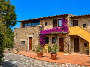 a stone house with purple flowers on it at Sunset Three Shared Pool 100m from the Beach in Baja Sardinia