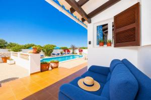 a living room with a blue couch and a pool at Villa Ca Nostra in Cala en Porter