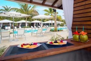 two plates of fruit on a table next to a pool at Serenity at Coconut Bay All Inclusive - Couples Only in Vieux Fort