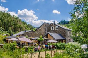 a building with tables and umbrellas in front of it at B&B Au Canard in La-Roche-en-Ardenne