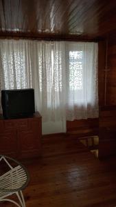 a living room with a television and a window at Dacha Pool and Grill in Karavan