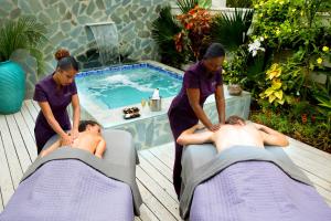 a woman giving a man a massage in front of a swimming pool at Serenity at Coconut Bay All Inclusive - Couples Only in Vieux Fort