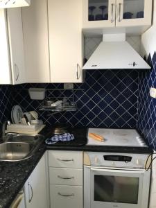 a small kitchen with white cabinets and blue tiles at Vue superbe in Port El Kantaoui +9 photos