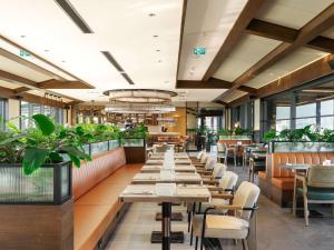 a restaurant with tables and chairs and plants at Novotel Tbilisi Center in Tbilisi City