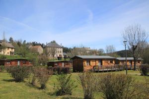 a log cabin in a field with houses in the background at Camping de Saint Just - Onlycamp in Arcomie