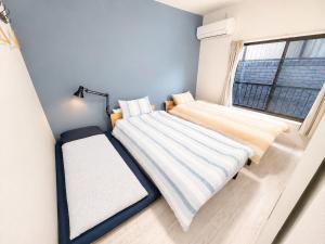two beds in a small room with a window at New Entire Family House 1 Min to Metro Umeda Direct in Osaka