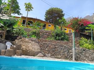 a house with a stone wall next to a swimming pool at Casa Das Ilhas in Paul