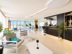 a living room with white furniture and plants at Hotel TYC in Rimini