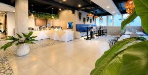 a restaurant with white tables and chairs and plants at Vadamar Hotel Collection Rodadero in Gaira