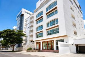 a white building with a tree in front of it at Vadamar Hotel Collection Rodadero in Gaira