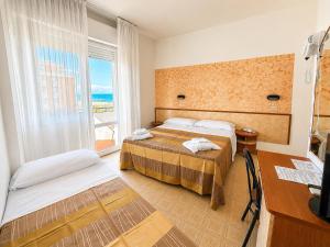 a hotel room with two beds and a desk and a window at Hotel TYC in Rimini