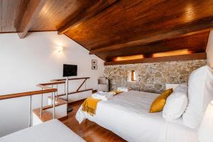 a bedroom with a bed and a stone wall at Quinta da Eira do Sol in Guimarães