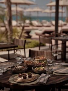 a wooden table with plates of food and wine glasses at OKU Bodrum in Golturkbuku