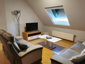 a living room with two couches and a tv at Gîte De L'Oie Blanche in Blodelsheim