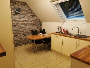 a kitchen with a table and a brick wall at Gîte De L'Oie Blanche in Blodelsheim +3 photos