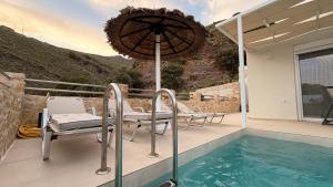 a patio with chairs and an umbrella next to a swimming pool at Villa Casa Solea in Myrthios