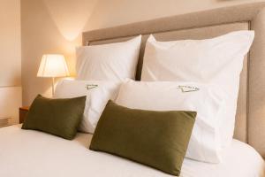 a bed with white pillows and green pillows at Quinta da Eira do Sol in Guimarães