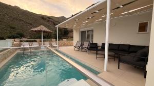 a house with a swimming pool with a couch and chairs at Villa Casa Solea in Myrthios