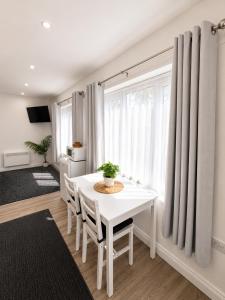 a white dining room with a white table and chairs at The Studio Room in Brentwood