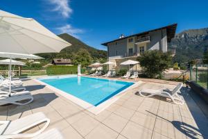 a swimming pool with chairs and a building at Recidence EMILIO in Ledro