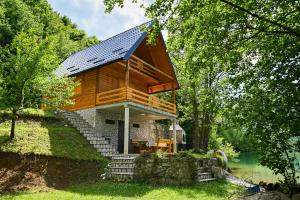 a small house with a metal roof on a lake at Cottage Sunshine in Jajce