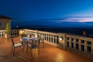 a table and chairs on a balcony at night at Sina Brufani in Perugia