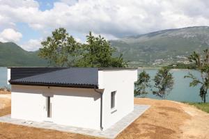 a small white building with a black roof next to a body of water at Holiday Home Paradise in Prozor