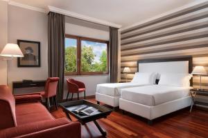 a hotel room with a white bed and a desk at Sina Maria Luigia in Parma +26 photos