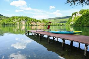 a dock with a chair and a kayak on a lake at Cottage Sunshine in Jajce +8 photos