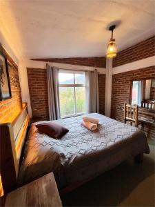 a bedroom with a bed with pillows and a window at La Misión Cabañas Chignahuapan in Chignahuapan