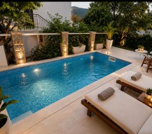 a swimming pool with two loungers next to a building at Apartman Taraca Villa Knezevic in Herceg-Novi