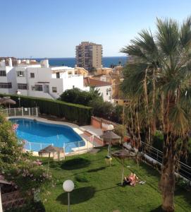 a view of a resort with a swimming pool and a palm tree at Casa Juana in Benalmádena