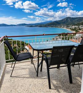 a table and chairs on a balcony with a view of the water at Nickolas Sea View Apartment in Paleo Tsifliki