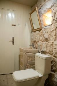 a bathroom with a white toilet and a stone wall at Bayt Broud in Gharīfah