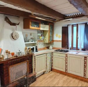 a kitchen with white cabinets and a clock on the wall at La casa di Fiore in Arcidosso +20 photos
