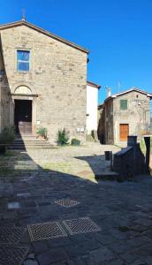 a large stone building with a door and a brick building at La casa di Fiore in Arcidosso