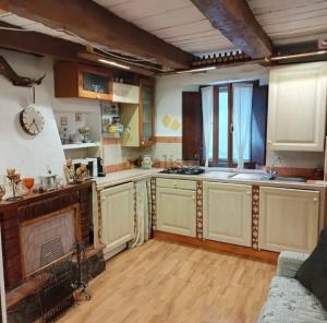 a large kitchen with wooden cabinets and a fireplace at La casa di Fiore in Arcidosso