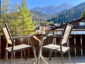 a table and two chairs on a balcony with mountains at Haus Anemona in Savognin +5 photos