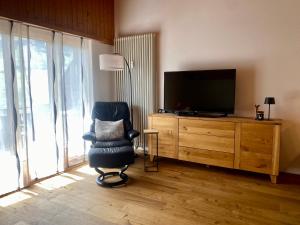 a living room with a chair and a television at Haus Anemona in Savognin